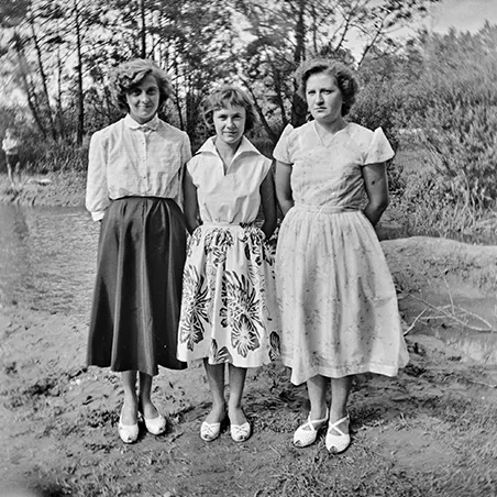 trzy kobiety w białych koszulach i spódnicach pozujące nad rzeką